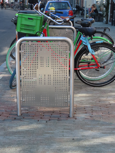 851055 Afbeelding van enkele 'fietsnietjes' waarin een silhouet van de Domtoren verwerkt is, met geparkeerde fietsen op ...